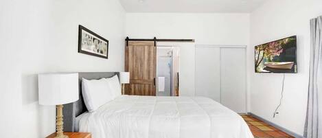 A hotel room with a bed, a wooden nightstand, a ceiling fan, a TV, and a sliding door.