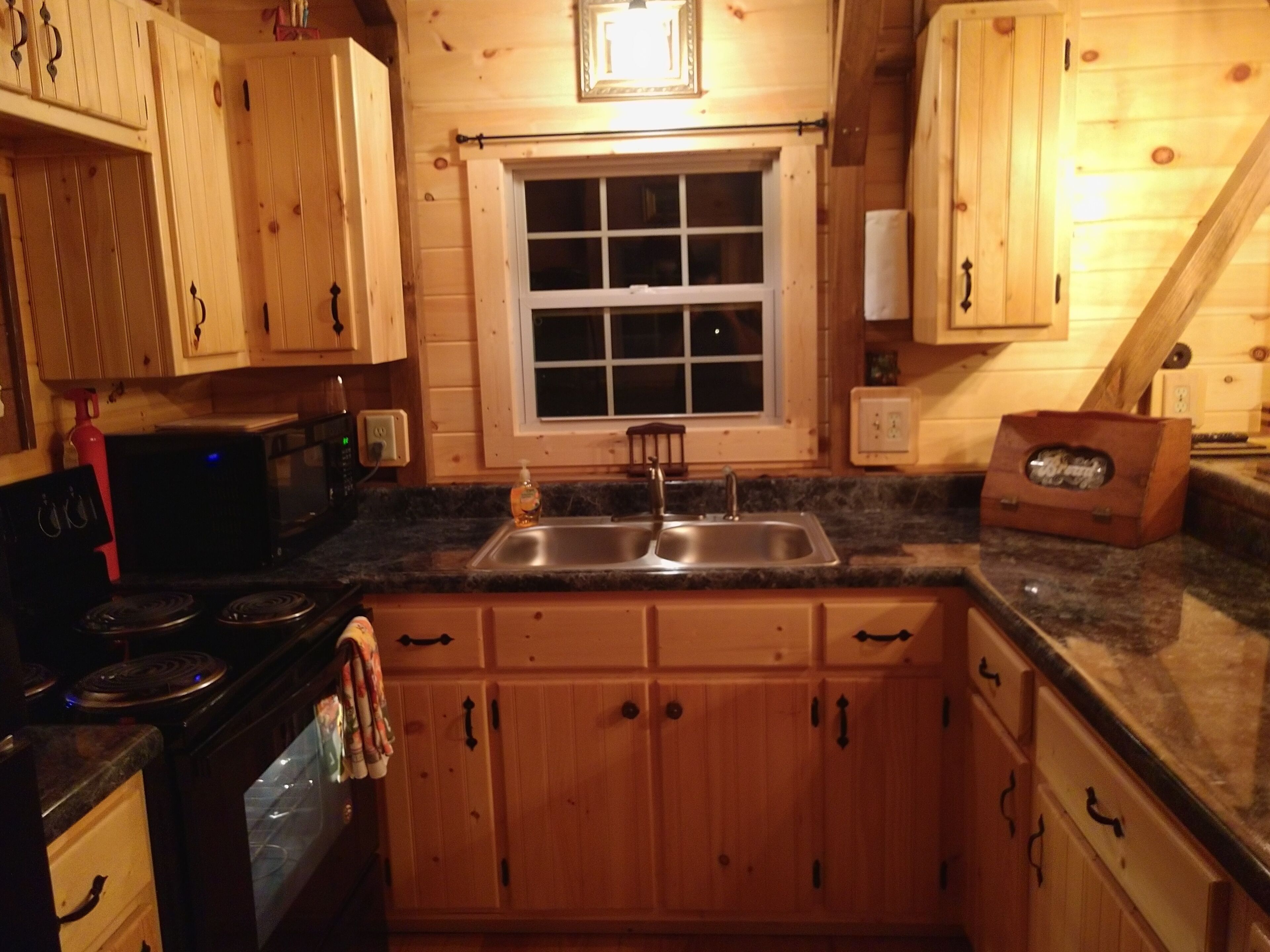 A kitchen with wooden cabinets, a granite countertop, a double sink, and a window above the sink.
