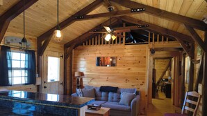 Een knus interieur van een chalet met houten plafond, een eethoek met een marmeren aanrechtblad, een bank en een stoel.