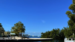 Vista calma da orla marítima com um cais, barcos e céu claro.