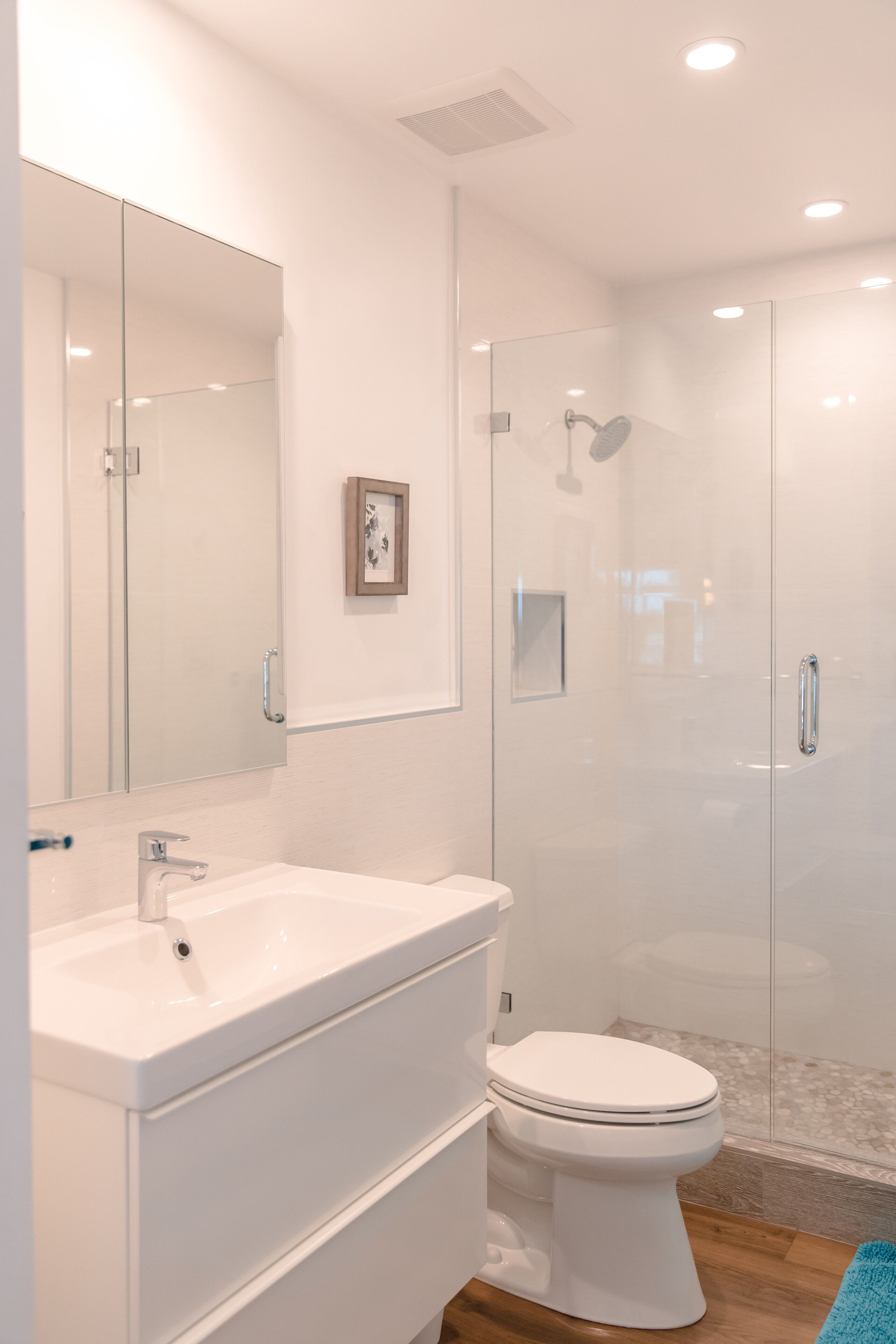 A modern bathroom with a glass-enclosed shower, a white sink, and a toilet.