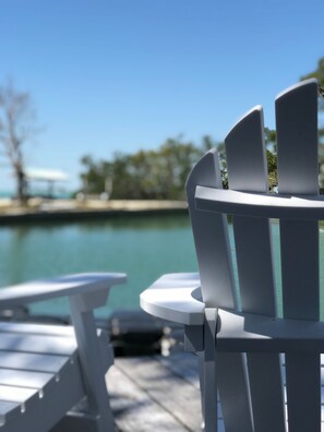 A white Adirondack chair facing a body of water with a clear sky. - 5 bedroom - Deep Dockage & Heated Pool in Islamorada. (Islamorada)
