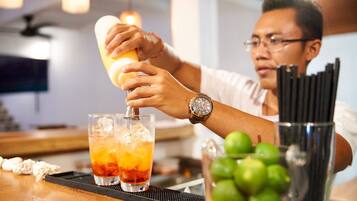 Een bartender bereidt een drankje toe met een cocktailshaker en twee glazen op een bargedeelte.