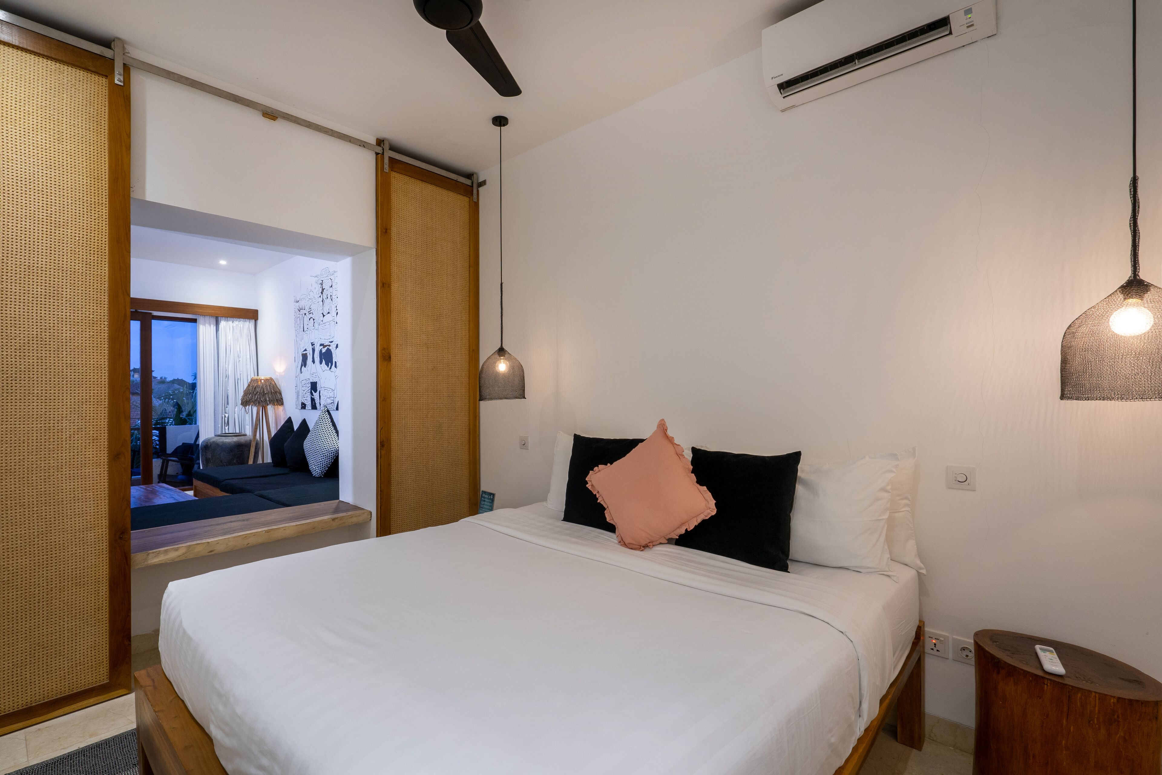 A modern hotel room with a large bed, a ceiling fan, an air conditioning unit, and a view of the outside.