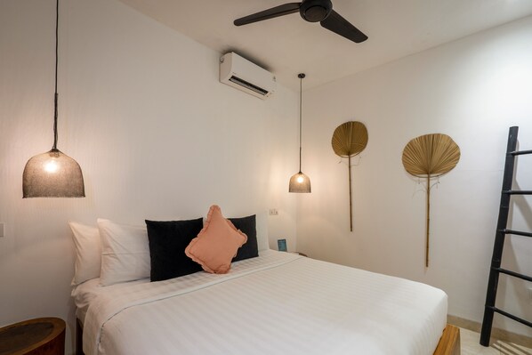 Un dormitorio con cama, ventilador de techo, aire acondicionado y lámparas de pared.