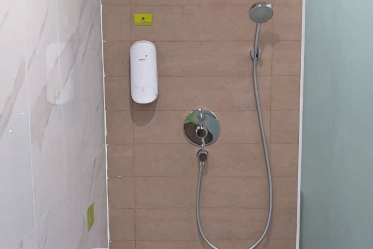 A shower area with a handheld showerhead and a wall-mounted control.