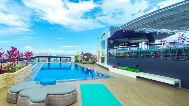 A rooftop pool area with a clear view of the city skyline, a children's play area, and a modern building with large windows. - MaxOneHotels.com at Balikpapan (Balikpapan)