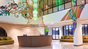 A modern lobby with a reception desk, sofas, and a large decorative chandelier. - MaxOneHotels.com at Balikpapan (Balikpapan)