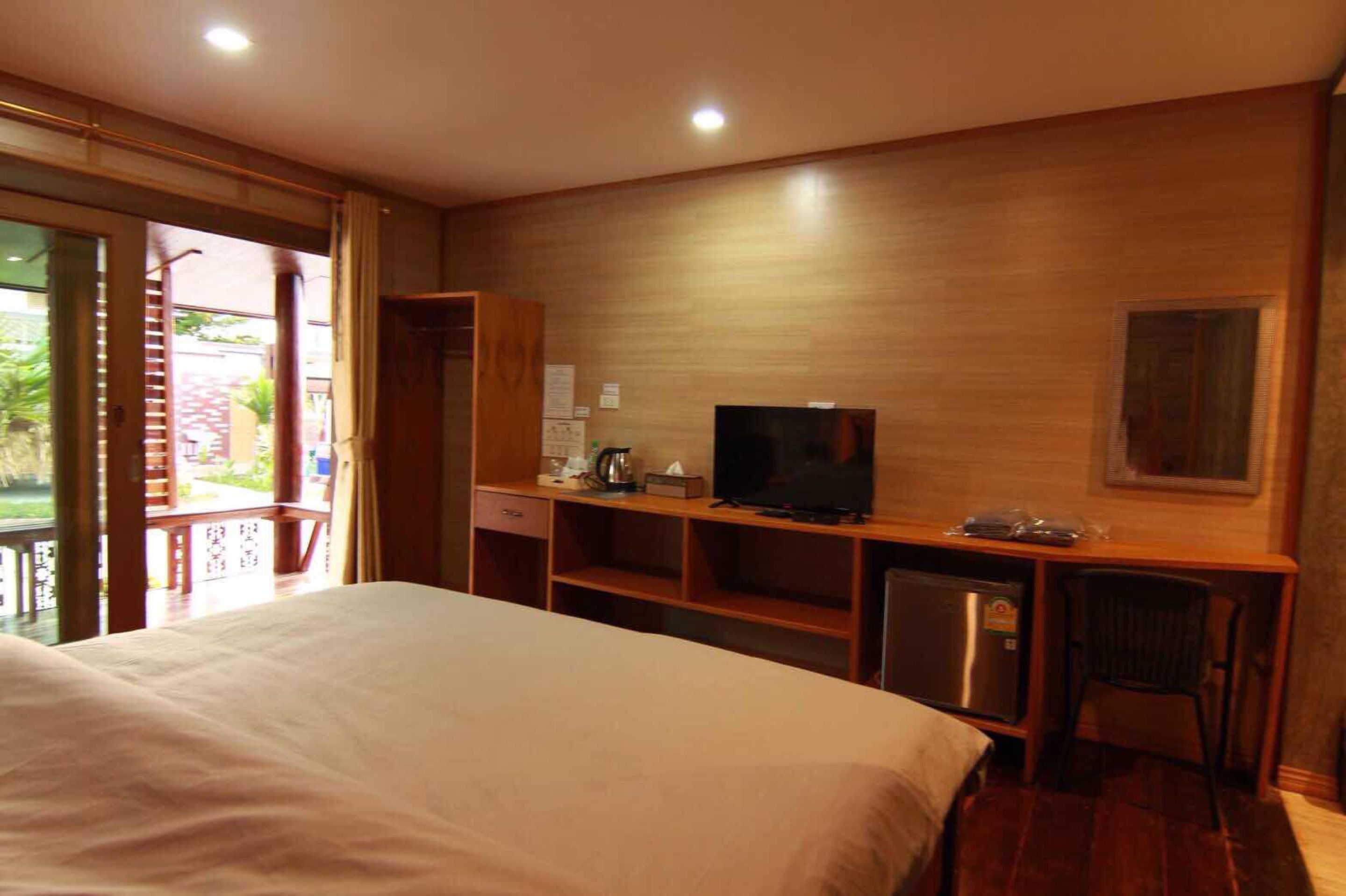 Habitación de hotel con cama, televisión, escritorio con silla y un refrigerador pequeño.