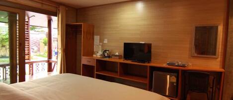 Habitación de hotel con cama, televisión, escritorio con silla y un refrigerador pequeño.