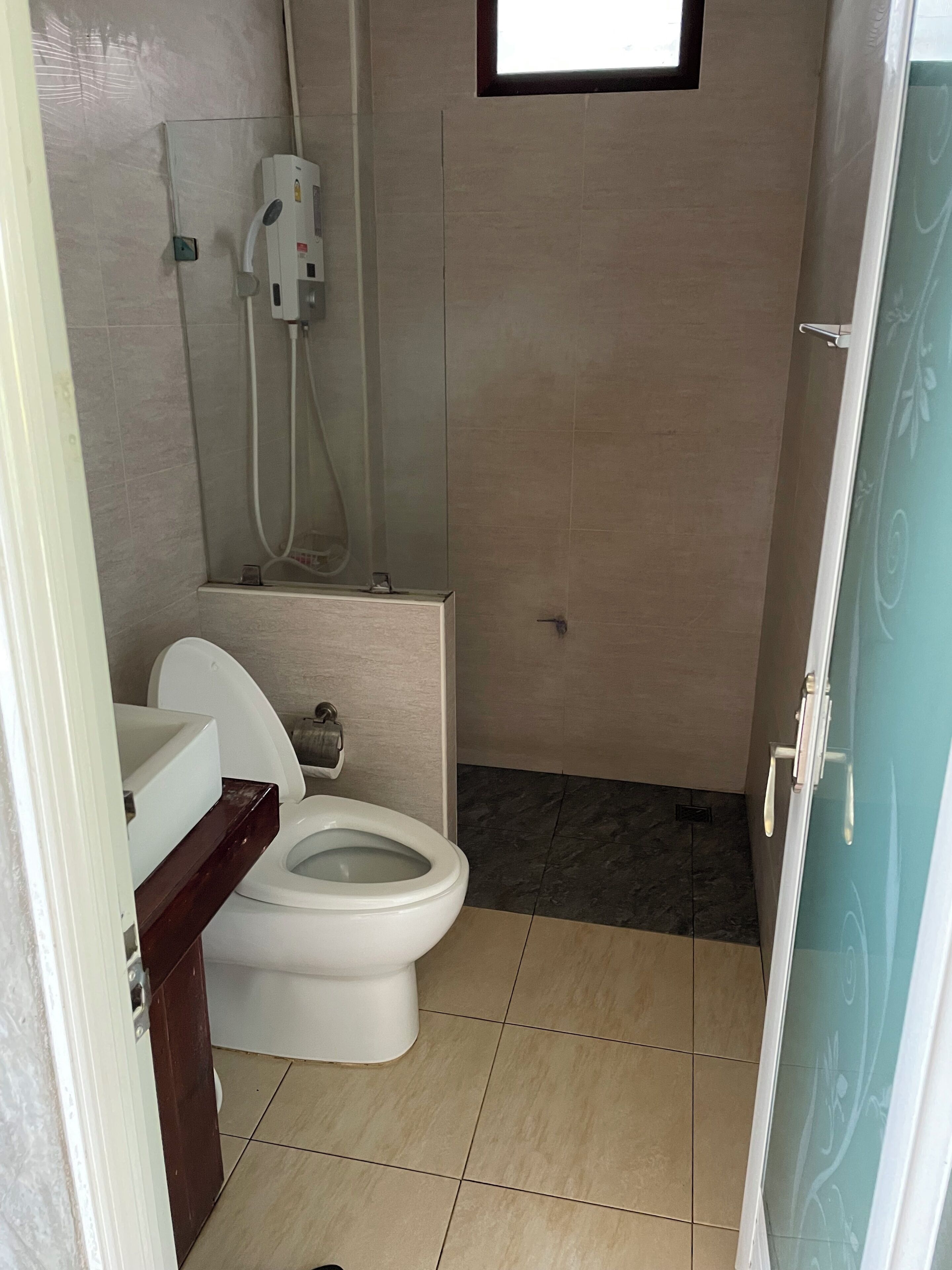 Een kleine, praktische badkamer met toilet, douche en wastafel.