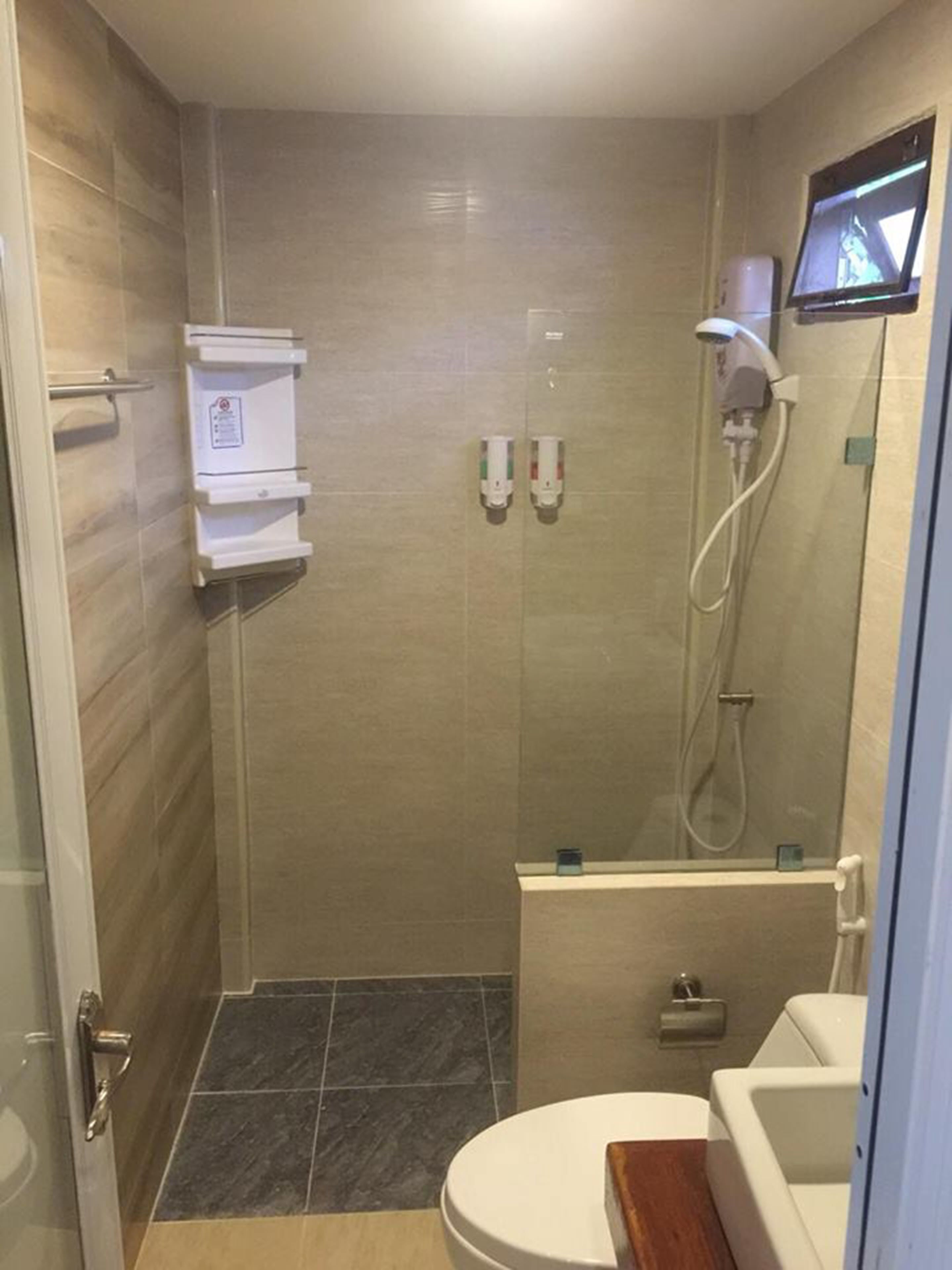 A small, modern bathroom with a shower, toilet, and a sink.