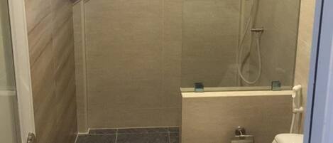 A small, modern bathroom with a shower, toilet, and a sink.
