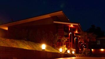 A modern house with a sloped roof, a brick exterior, and multiple illuminated windows at night.