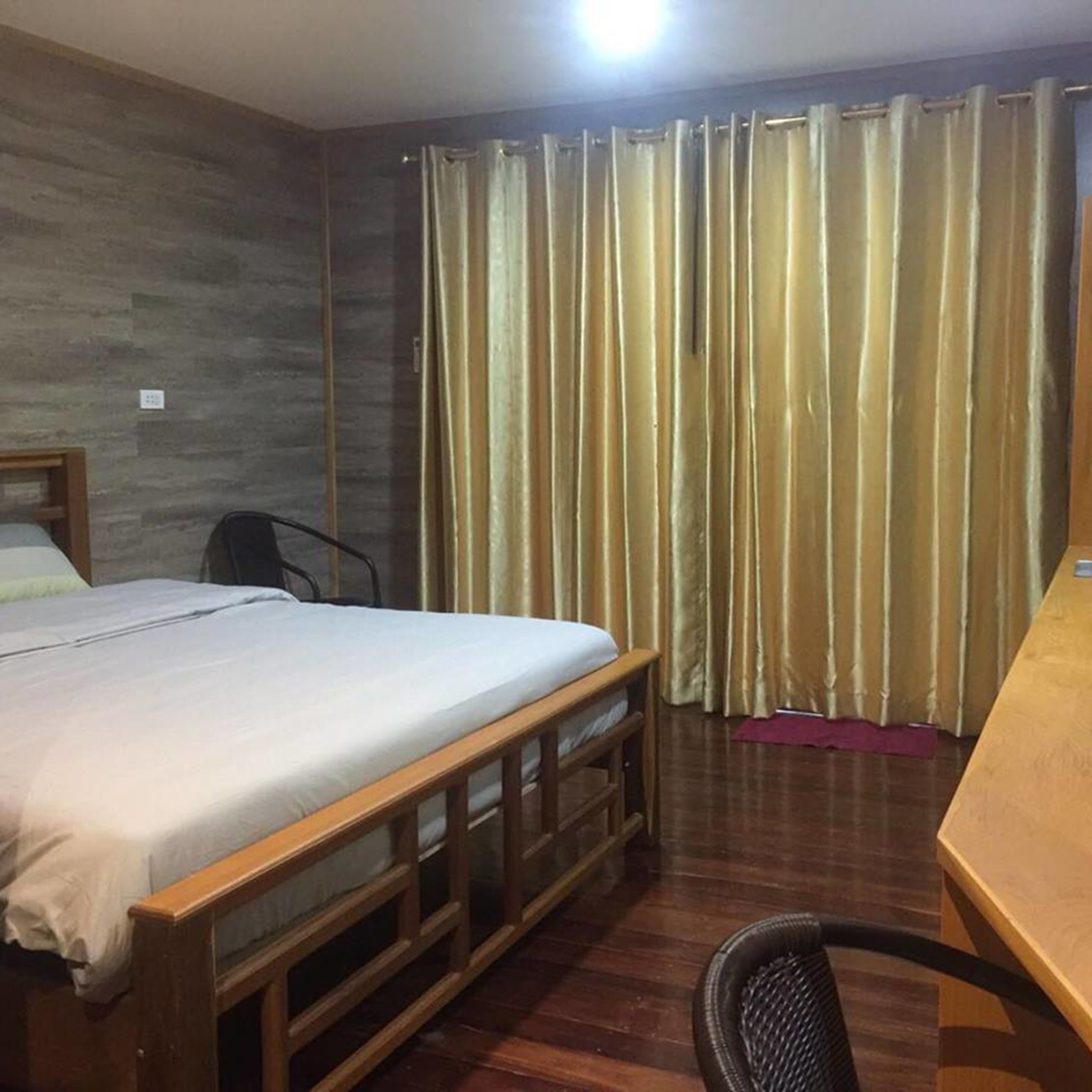 Una habitación con cama, escritorio, silla y cortina.