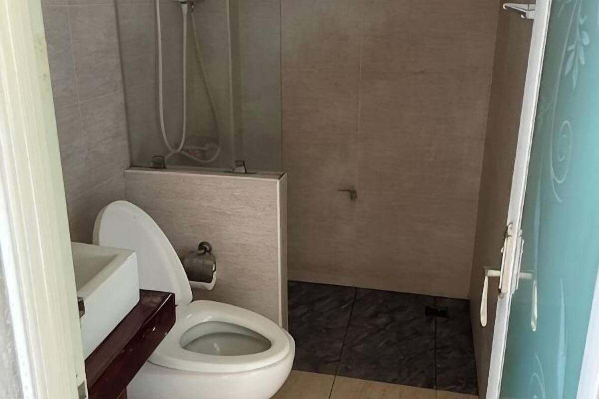 A bathroom with a toilet, shower, and a door with a handle.