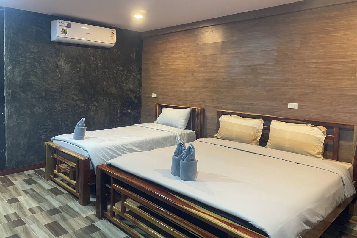 A hotel room with two beds, a wooden headboard, a marble wall, and an air conditioning unit.