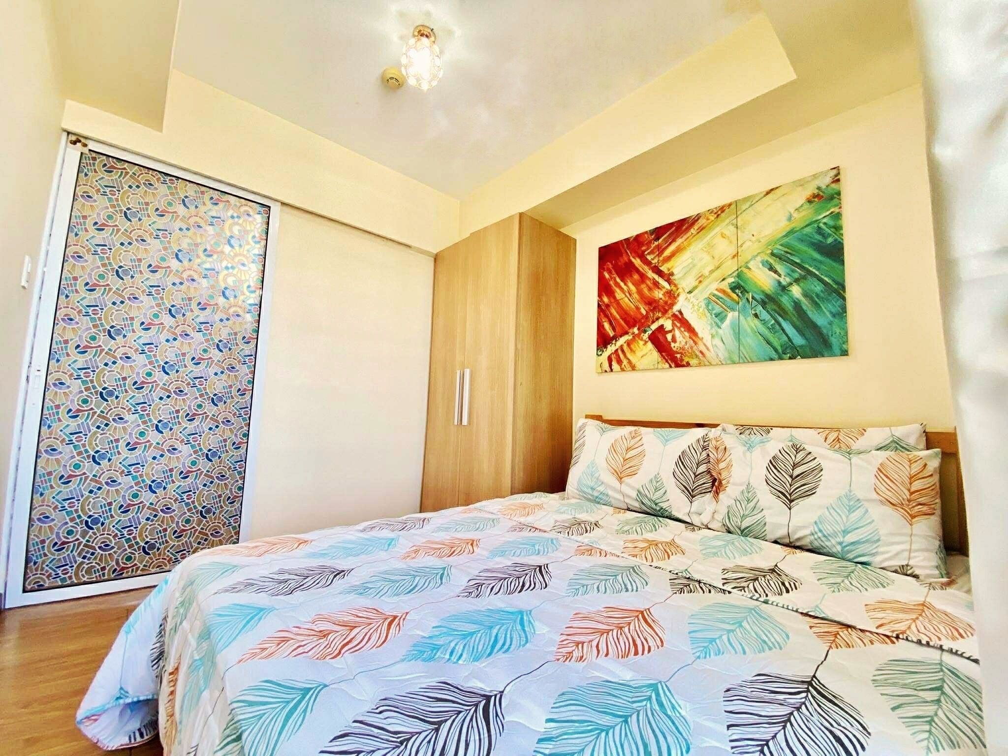 Quarto com cama, guarda-roupa e um quadro na parede.