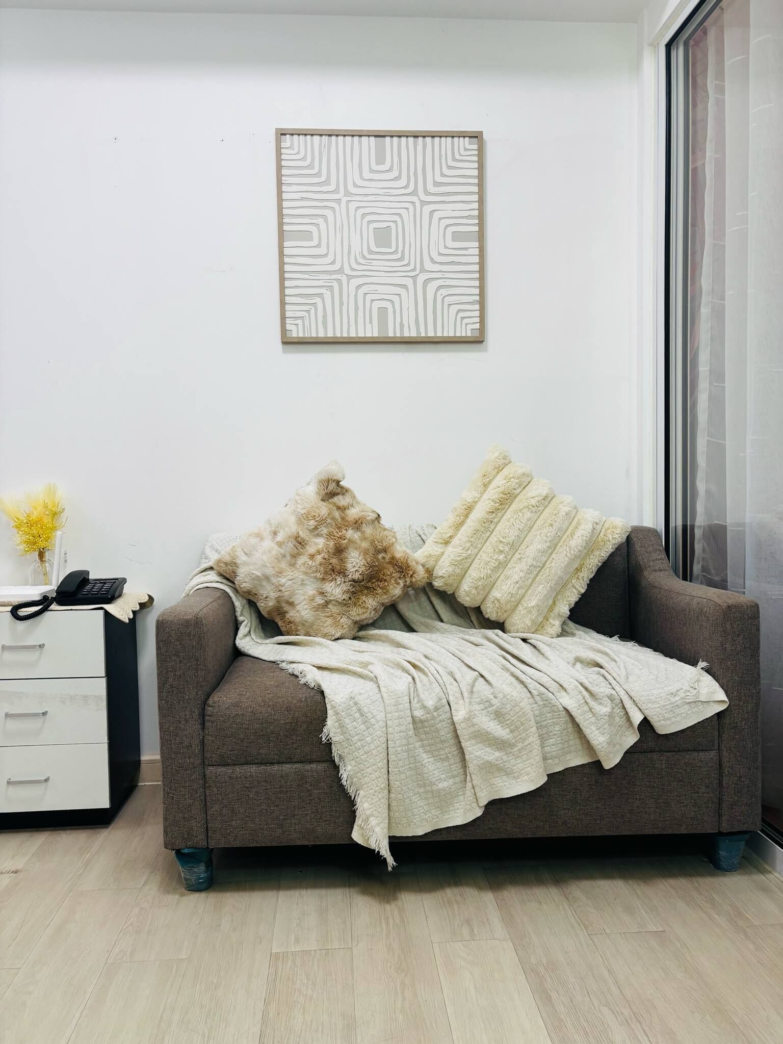 Una sala de estar moderna con un sofá gris, una manta blanca y un tapiz decorativo.