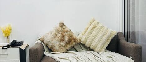 Una sala de estar moderna con un sofá gris, una manta blanca y un tapiz decorativo.