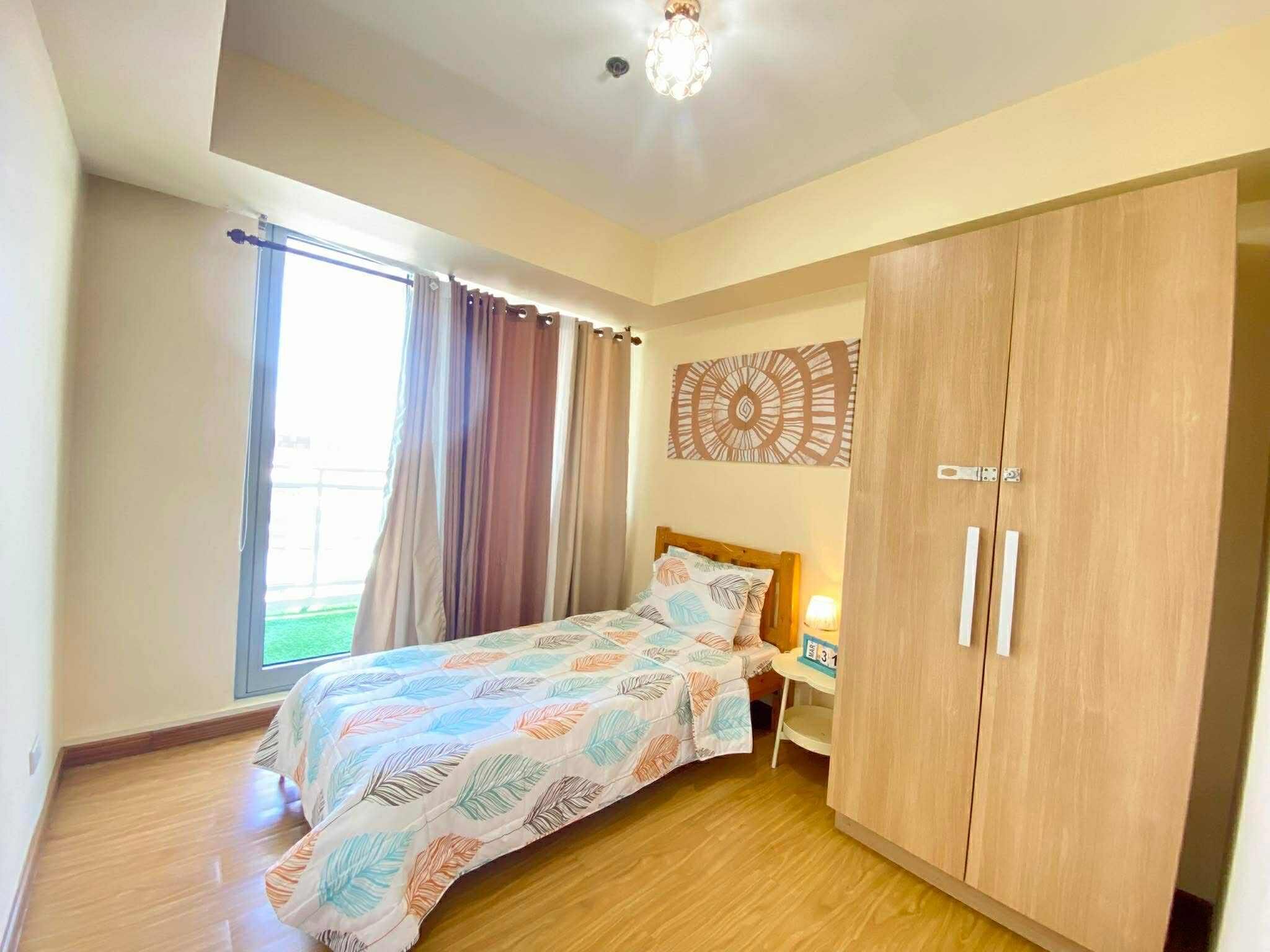 Een slaapkamer met een bed, een houten garderobe en een raam met gordijnen.