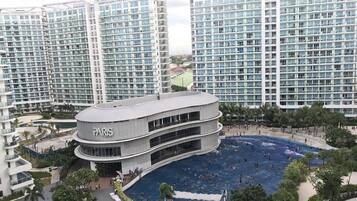 Un hotel moderno con una gran piscina rodeada de palmeras y vistas a rascacielos.
