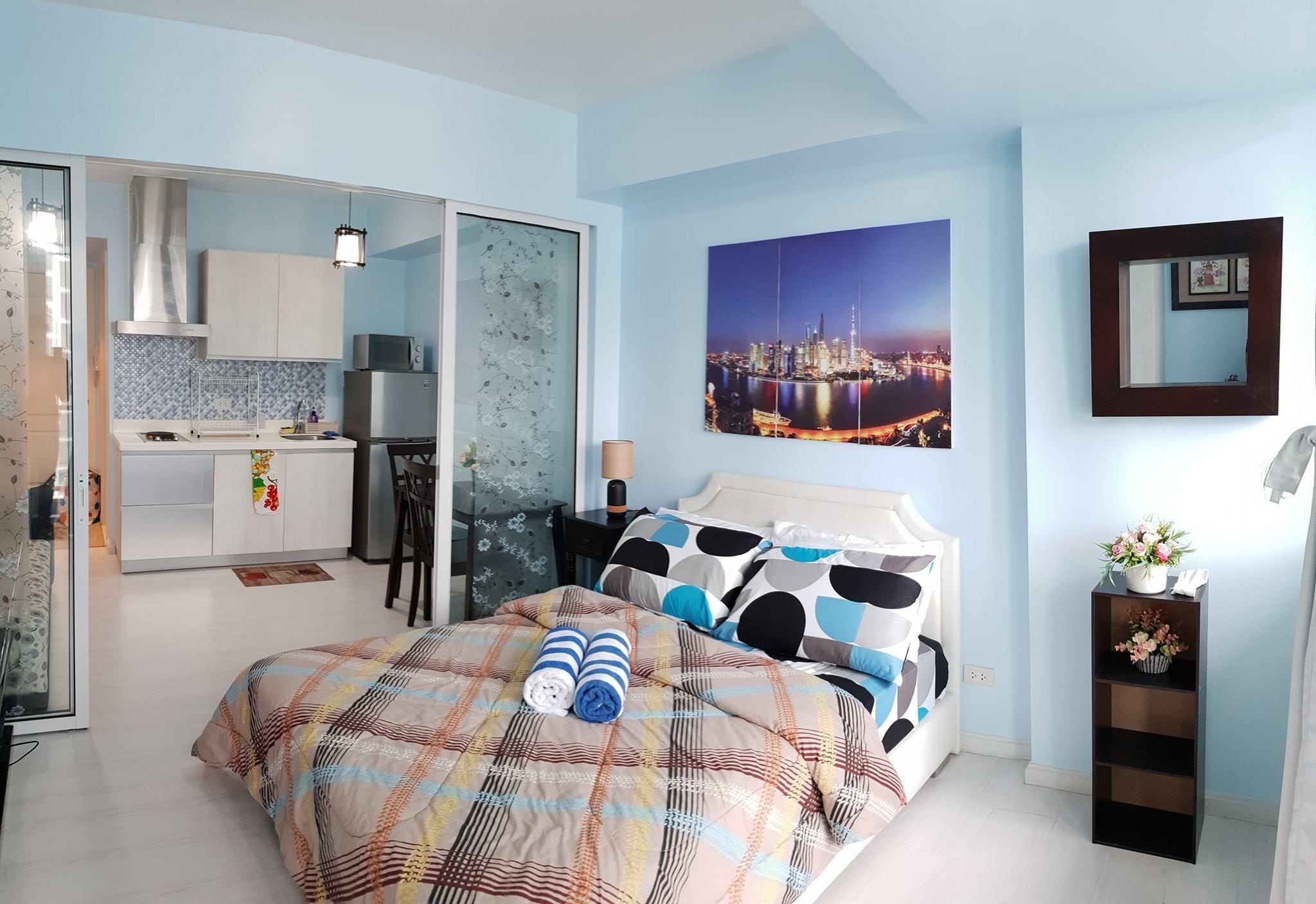 Un dormitorio con una cama, una mesita de noche y vistas a un paisaje urbano.