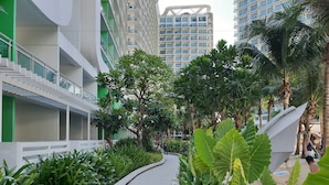Een modern gebouw met een gebogen pad omzoomd door tropische planten en palmbomen.