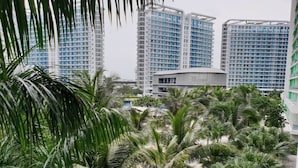 Een modern gebouwcomplex met meerdere hoge torens, omgeven door weelderige palmbomen.