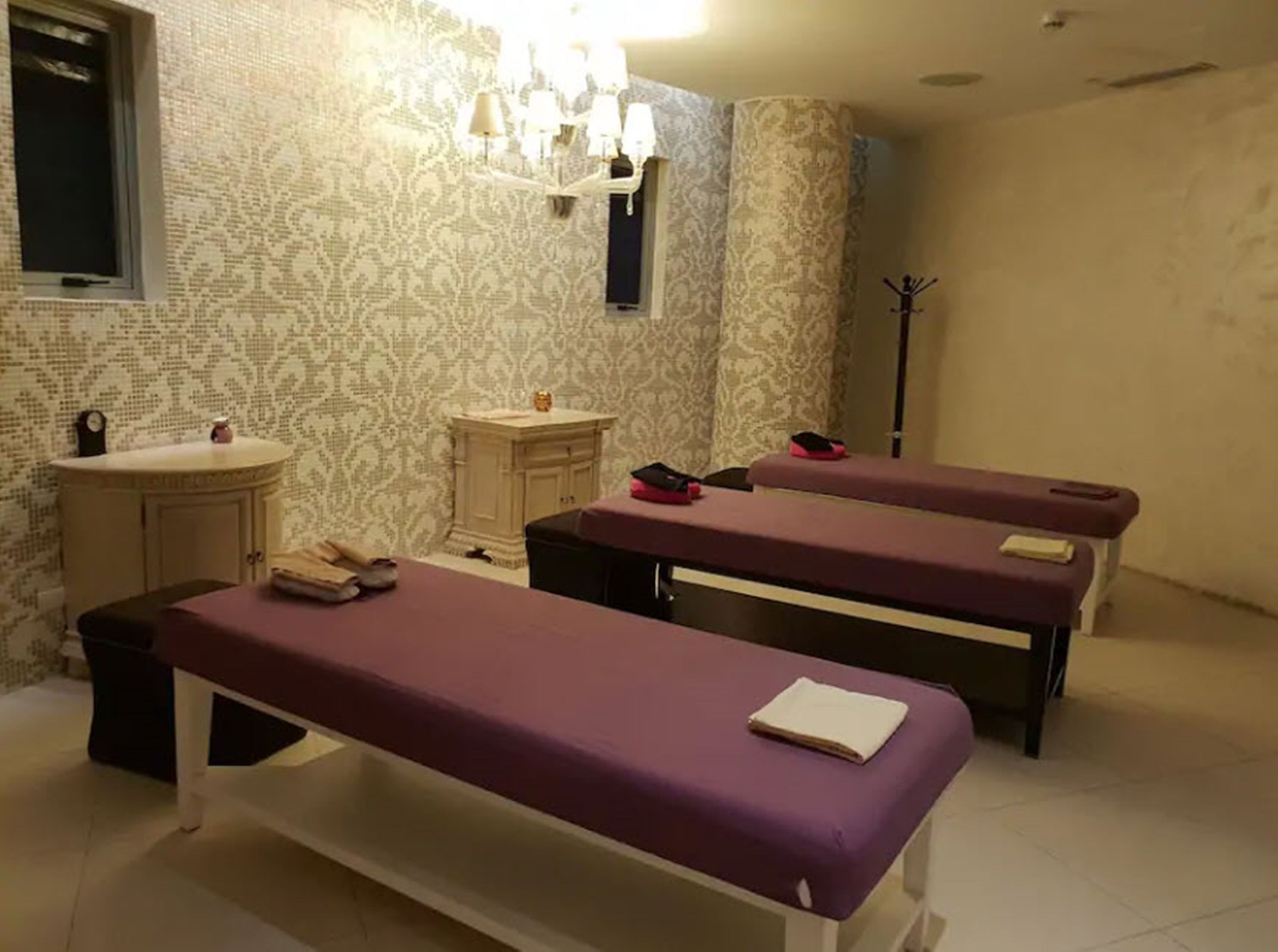 Um quarto com duas macas de massagem, uma pia pequena e um lavatório com espelho.