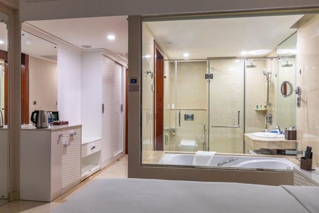Un baño moderno con ducha envuelta en vidrio, una bañera grande y una zona separada para el lavabo.