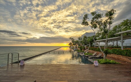 A wooden deck with a pool, lounge chairs, and a no diving sign.