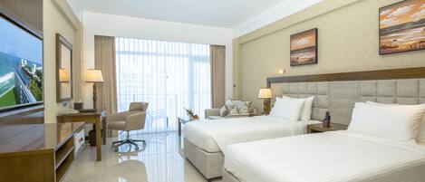Une chambre d’hôtel avec deux lits, un bureau, une chaise et un téléviseur.
