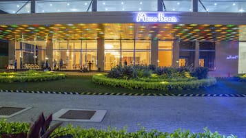 The exterior of Marino Beach hotel with a glass facade, outdoor seating area, and well-maintained landscaping.