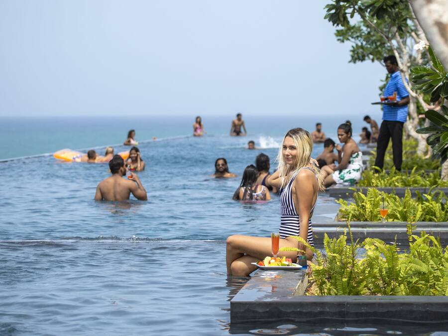 Un área de piscina con gente nadando y descansando.