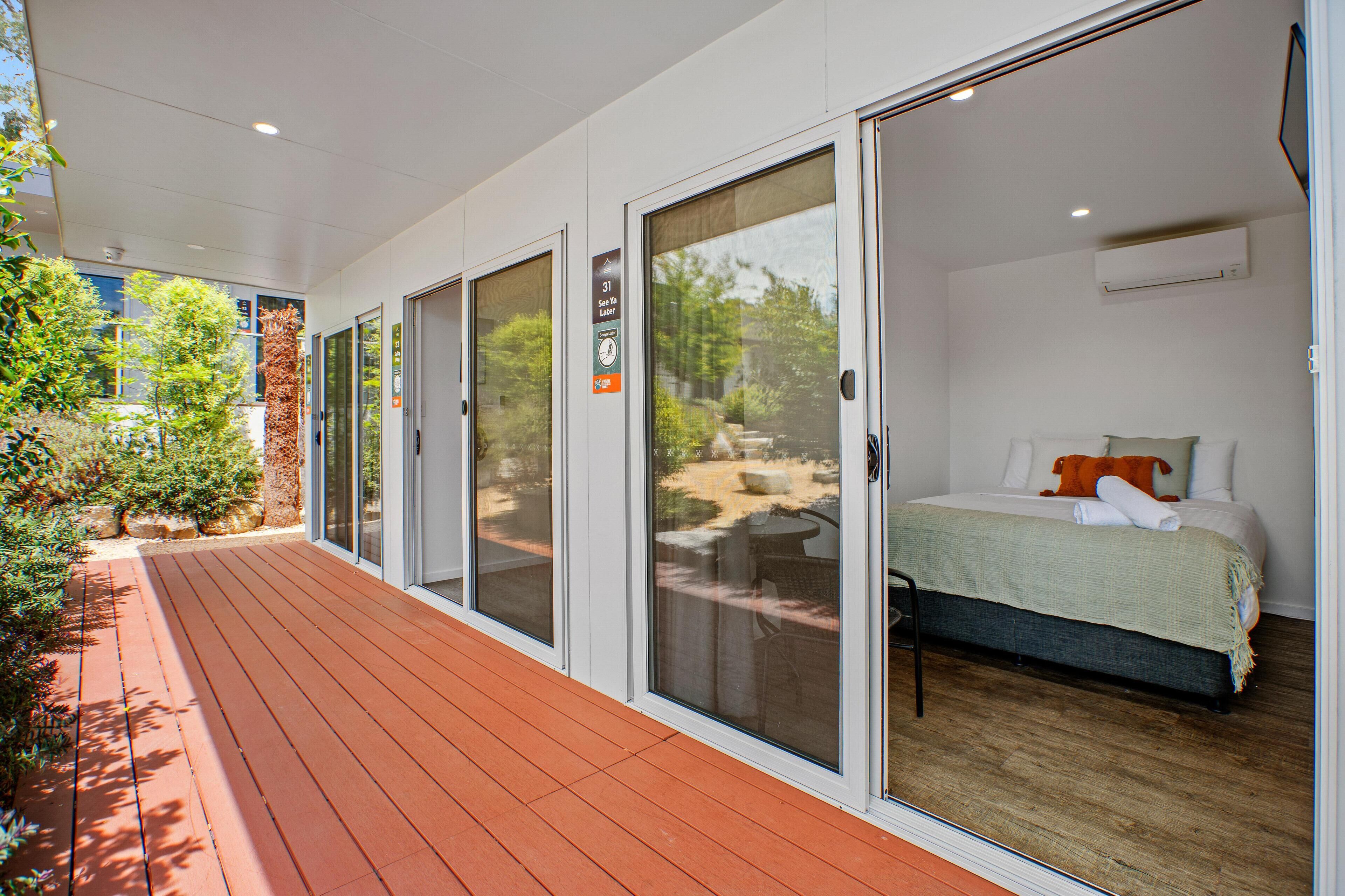 A hotel room with a bed, a view of the outdoors, and a sliding glass door leading to a patio area.