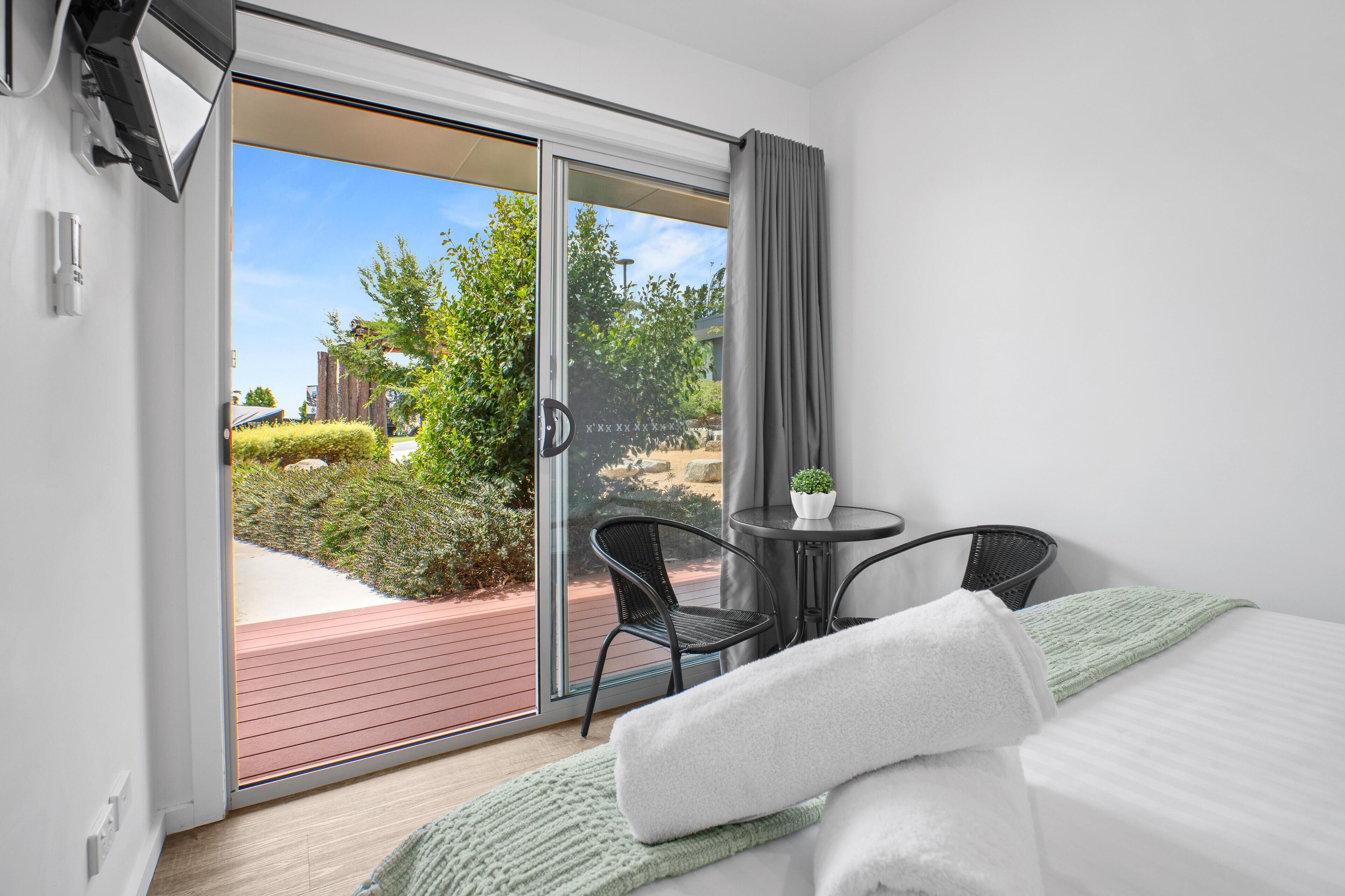 A hotel room with a bed, a small table with a plant, and a chair.