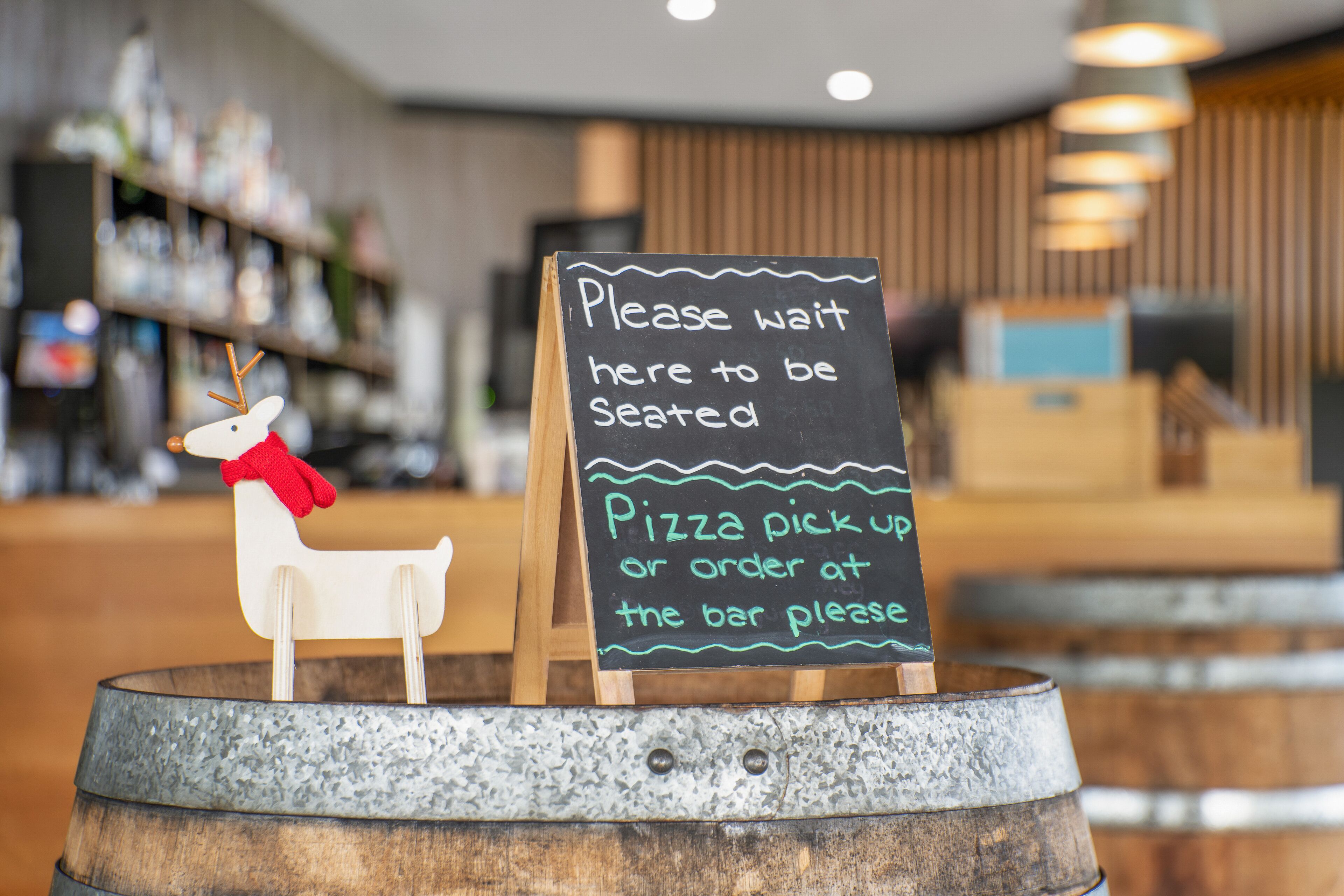 Ein Schild mit Anweisungen zum Sitzplatz und zur Pizzaabholung an einer Bar.