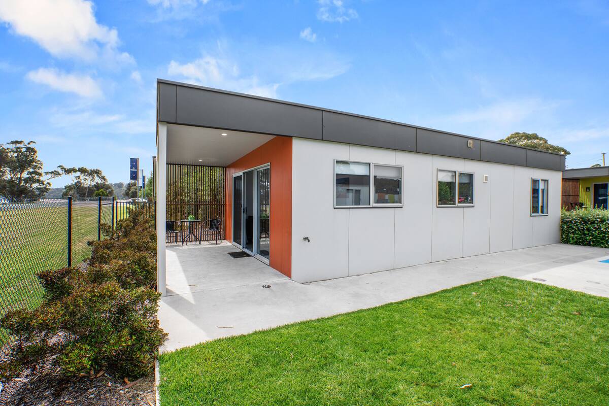 A modern building with a flat roof, large windows, and a covered entrance area.