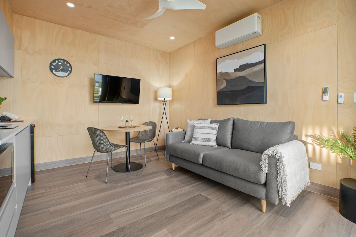 A modern living room with a grey sofa, a round table, and a TV.