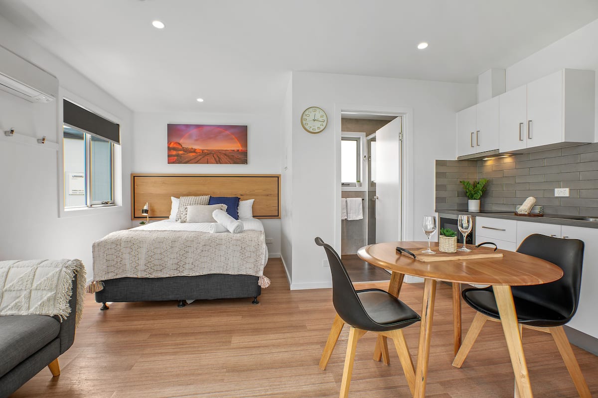 A modern bedroom with a bed, bedside table, and a view of the cityscape.