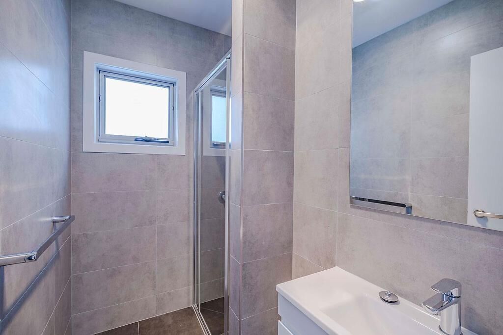 A bathroom with a shower, a window, and a mirror.