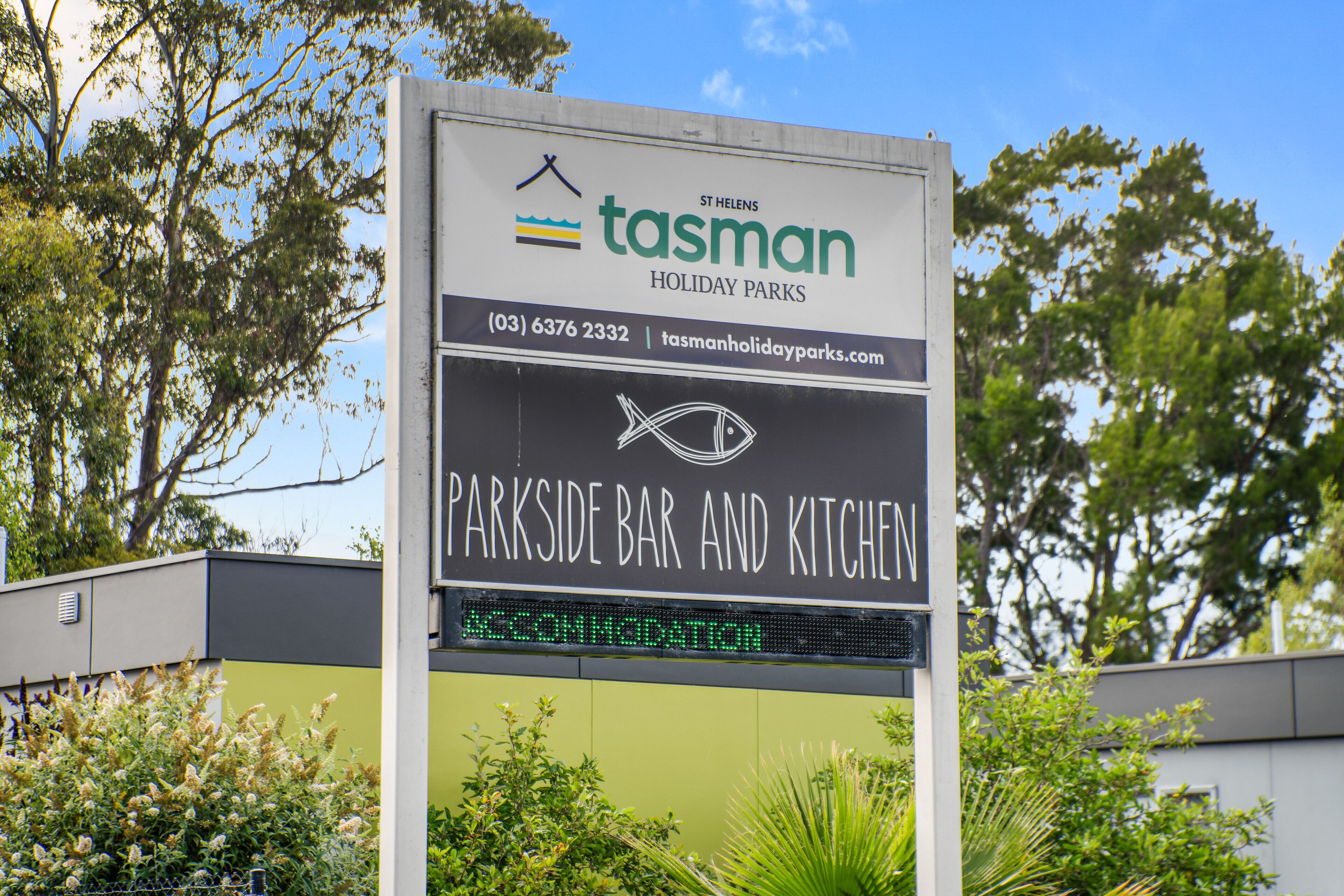 A sign for Tasman Holiday Parks with a contact number and website.