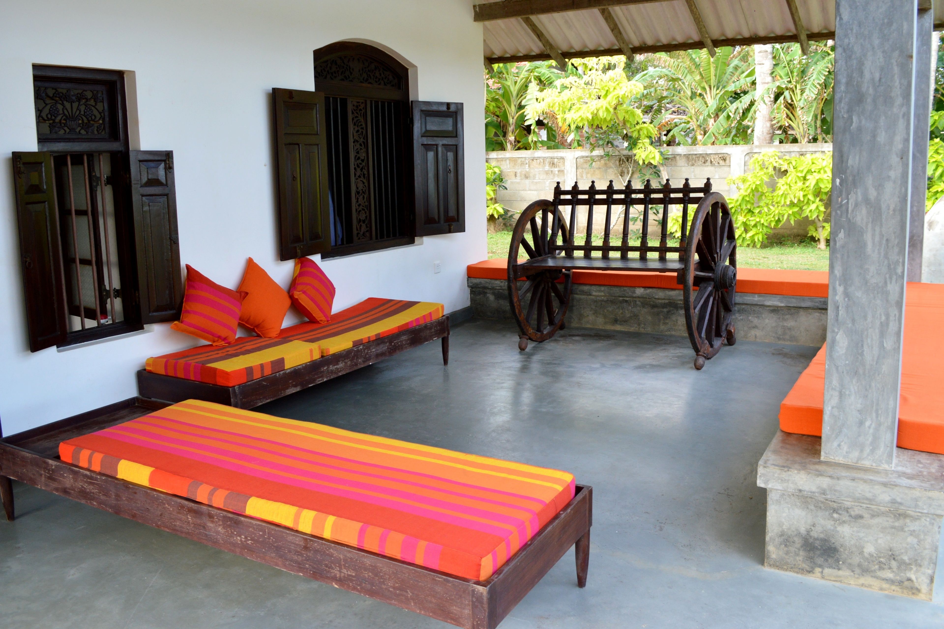 A room with a bed, a bench, and a wheelbarrow.