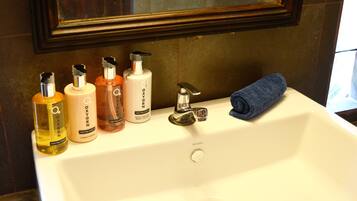 A bathroom sink with four bottles of body care products and a blue towel.