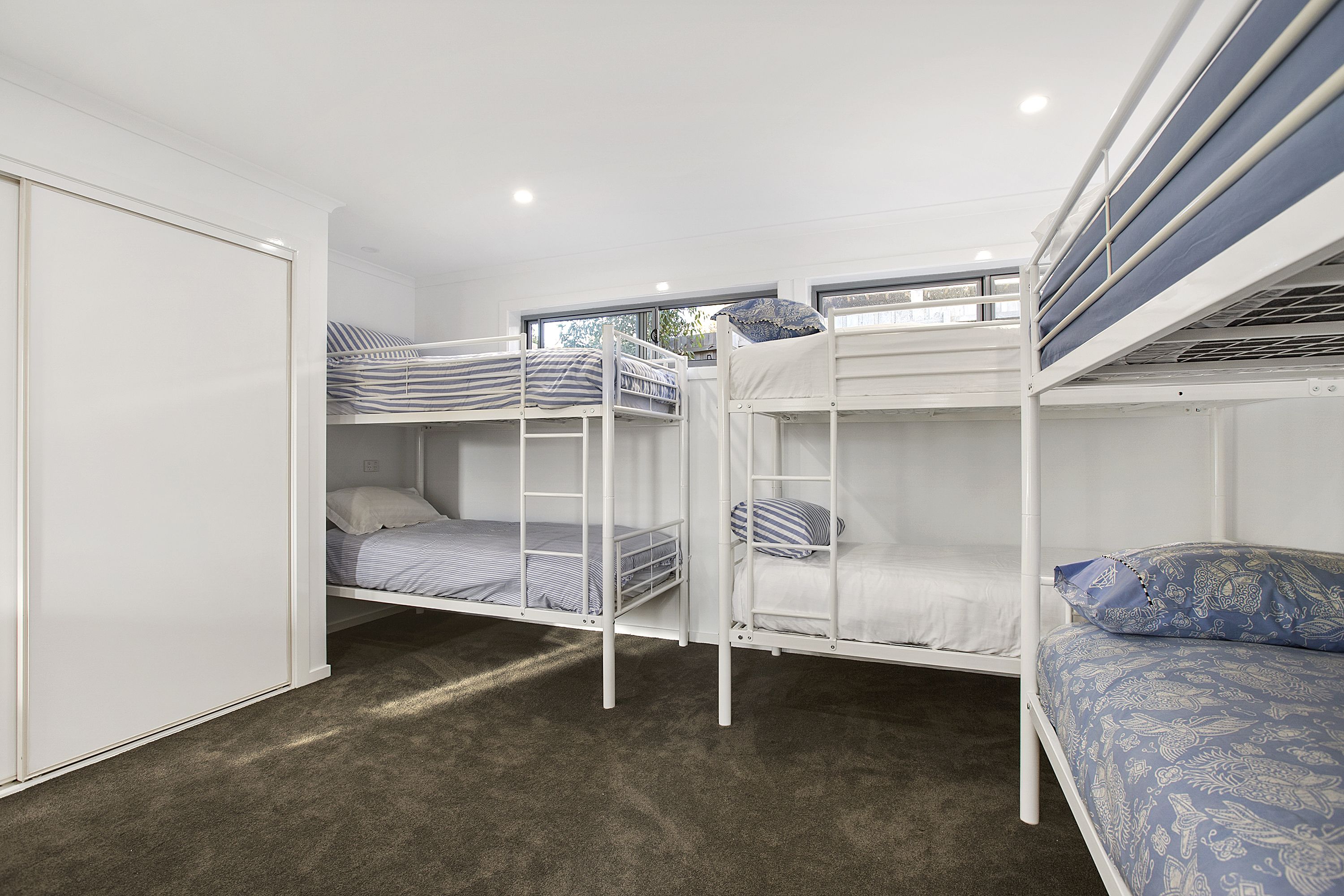A bunk bed room with a wardrobe and a window.