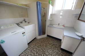 A small, compact bathroom with a washing machine, a sink, and a shower. - Air conditioned *ground floor own carport * Sheets/Towels not included (Hat Head)