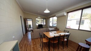 Un espacio habitable compacto con comedor, sofá y televisor.