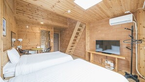 A wooden cabin room with a bed, a TV, and a brick wall. - Jeju Healing Resort (Jeju City)