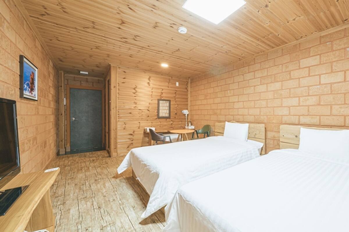 Een kamer met twee bedden, een bureau, een stoel en een televisietoestel.